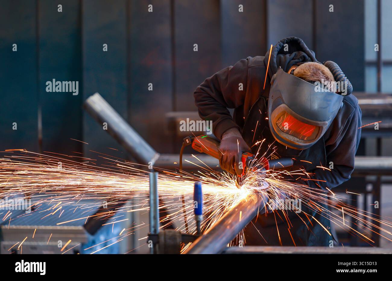 Deutschland - Themenfoto: Metallindustrie. Ein Industriearbeiter schneidet ein Stahlrohr mit einem Winkelschleifer. Stockfoto