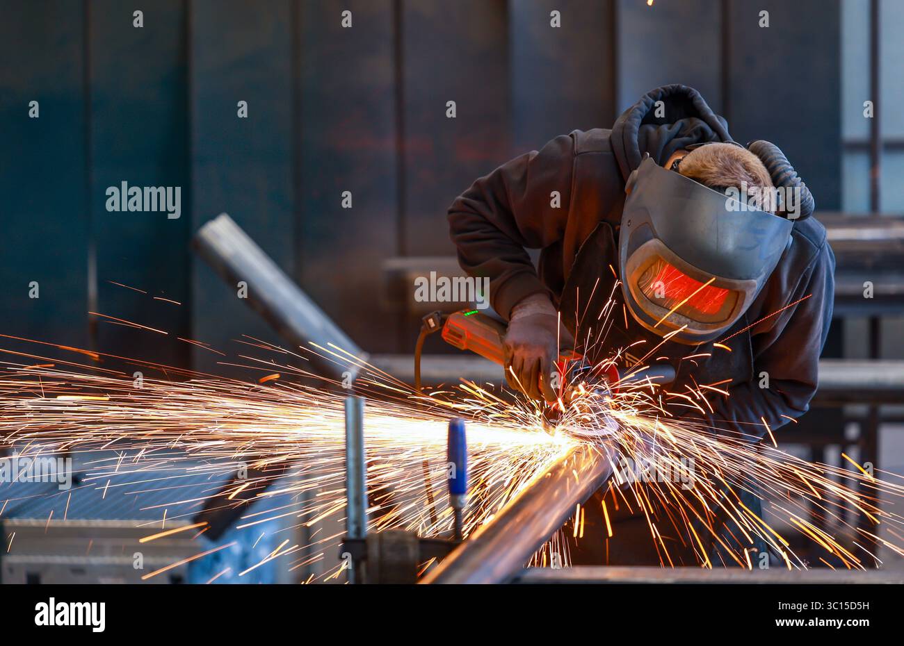 Deutschland - Themenfoto: Metallindustrie. Ein Industriearbeiter schneidet ein Stahlrohr mit einem Winkelschleifer. Stockfoto