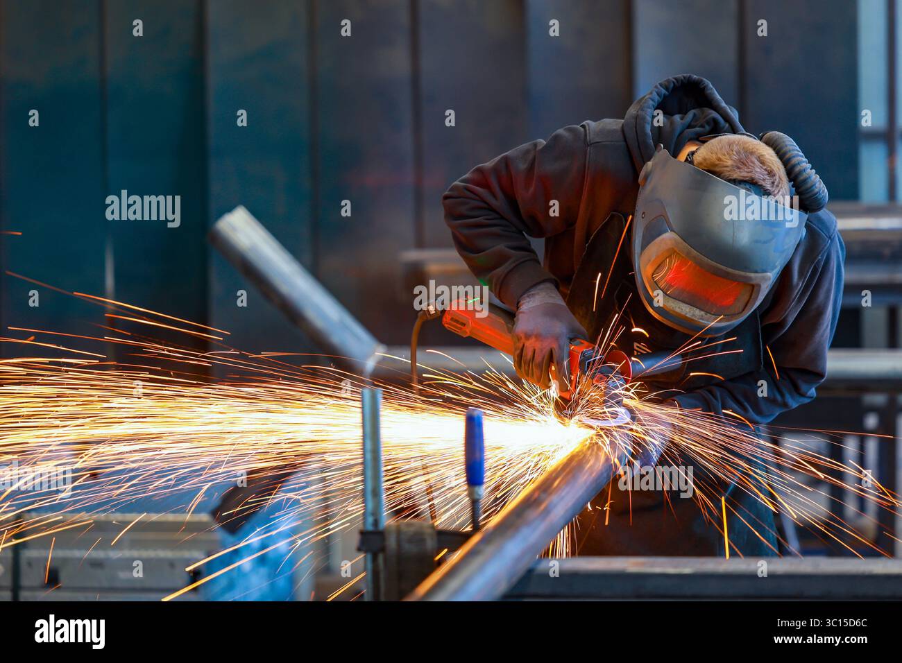 Deutschland - Themenfoto: Metallindustrie. Ein Industriearbeiter schneidet ein Stahlrohr mit einem Winkelschleifer. Stockfoto