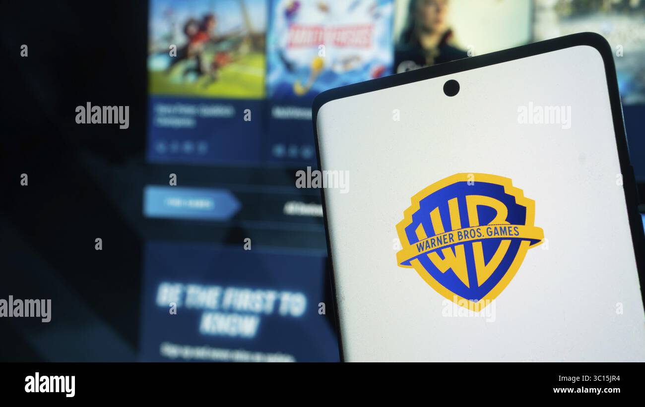 Das Smartphone zeigt das Warner Bros Games-Logo vor einer Gaming-Oberfläche an Stockfoto