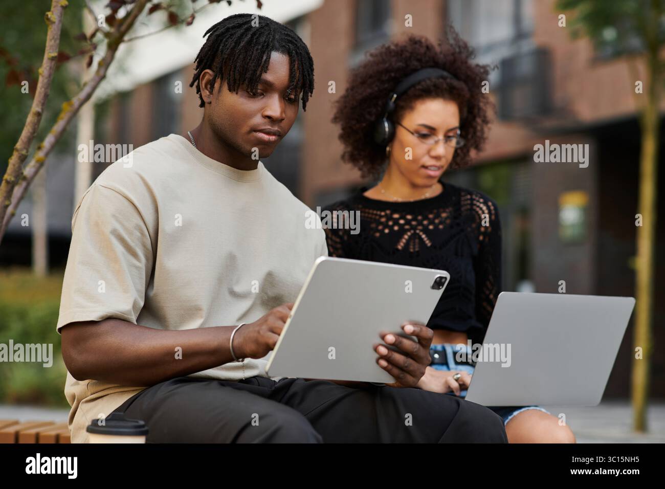 Ein junges Paar arbeitet im Freien zusammen und teilt Ideen auf seinem Laptop. Stockfoto