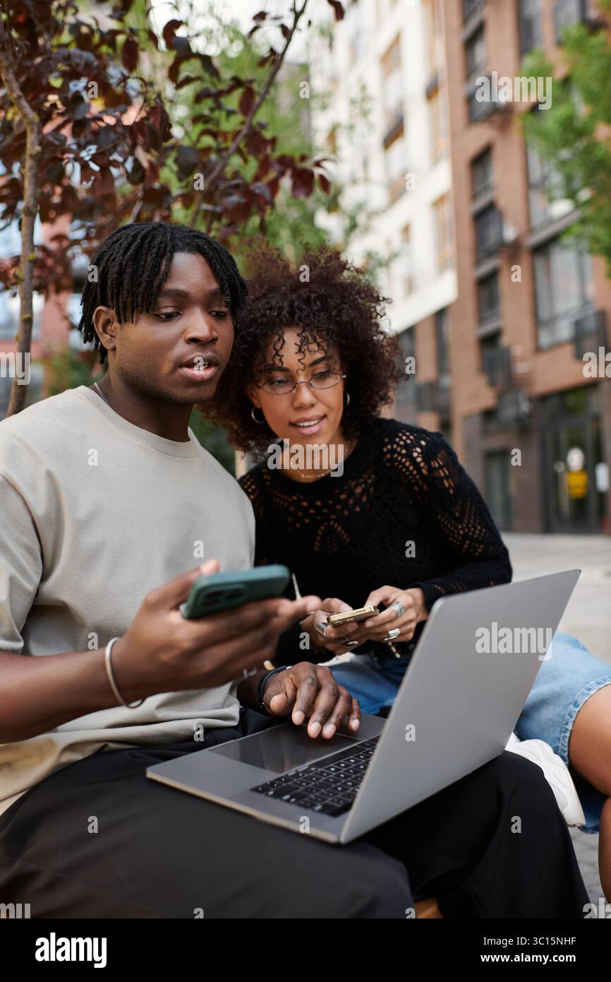 Ein junges afroamerikanisches Paar arbeitet im Freien zusammen und verbindet Stil und Zusammenarbeit aus der Ferne. Stockfoto