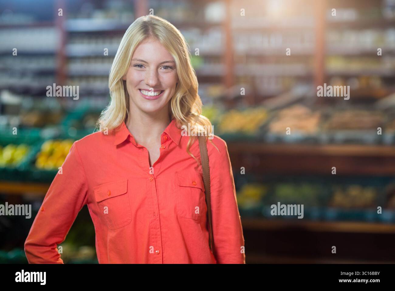 Weibliche Käuferinnen, die in einem Lebensmittelgeschäft stehen, produzieren Gänge, untersuchen die Behälter und tragen Tragetasche Stockfoto