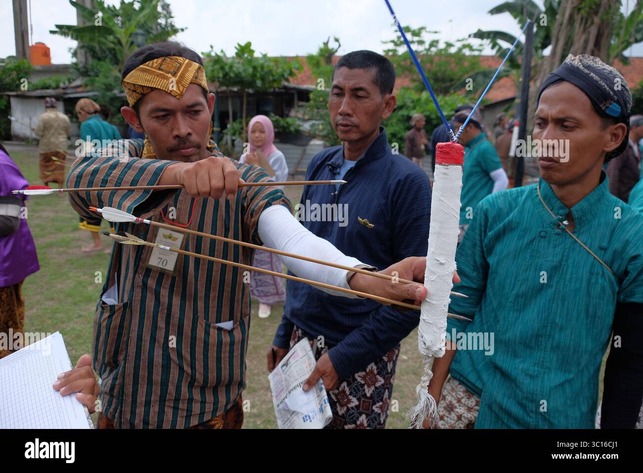 Ein Mann zieht einen Pfeil heraus, der während eines traditionellen javanischen Bogenschießsports, Jemparingan, in der Oberfläche eines Ziels steckt. Stockfoto