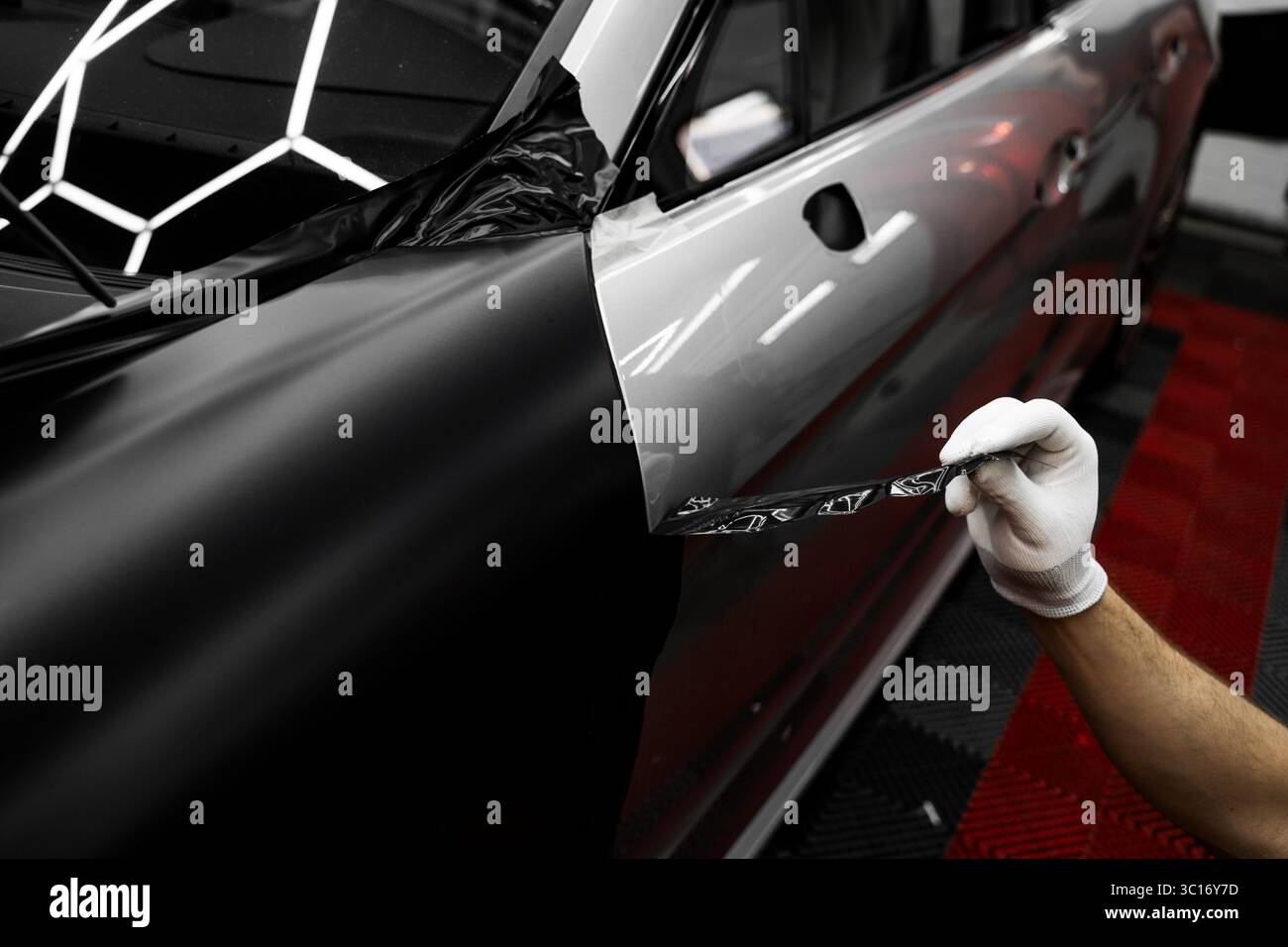 Die Anwendung „Auto Wrap“ ändert das Erscheinungsbild des Fahrzeugs. Vinyl-Verpackung Für Autos Mit Vollpaneel. Die großformatige Vinylfolie verwandelt das Außendesign des Fahrzeugs Stockfoto