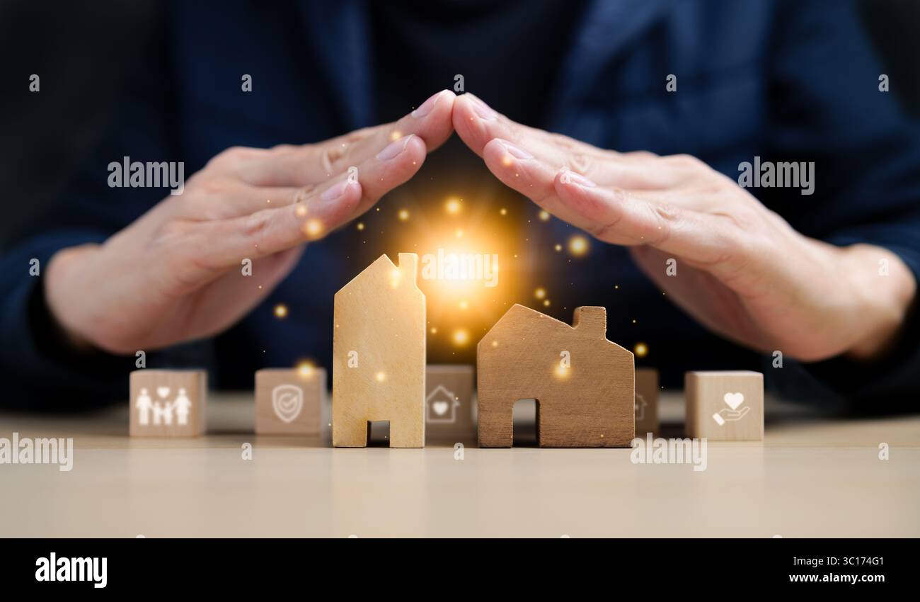 Versicherung Haus und Familie Gesundheit leben Konzept. Eine Hand, die ein Modell eines Hauses mit einigen Holzblöcken bedeckt. Immobilienversicherung, Hausschutz Stockfoto