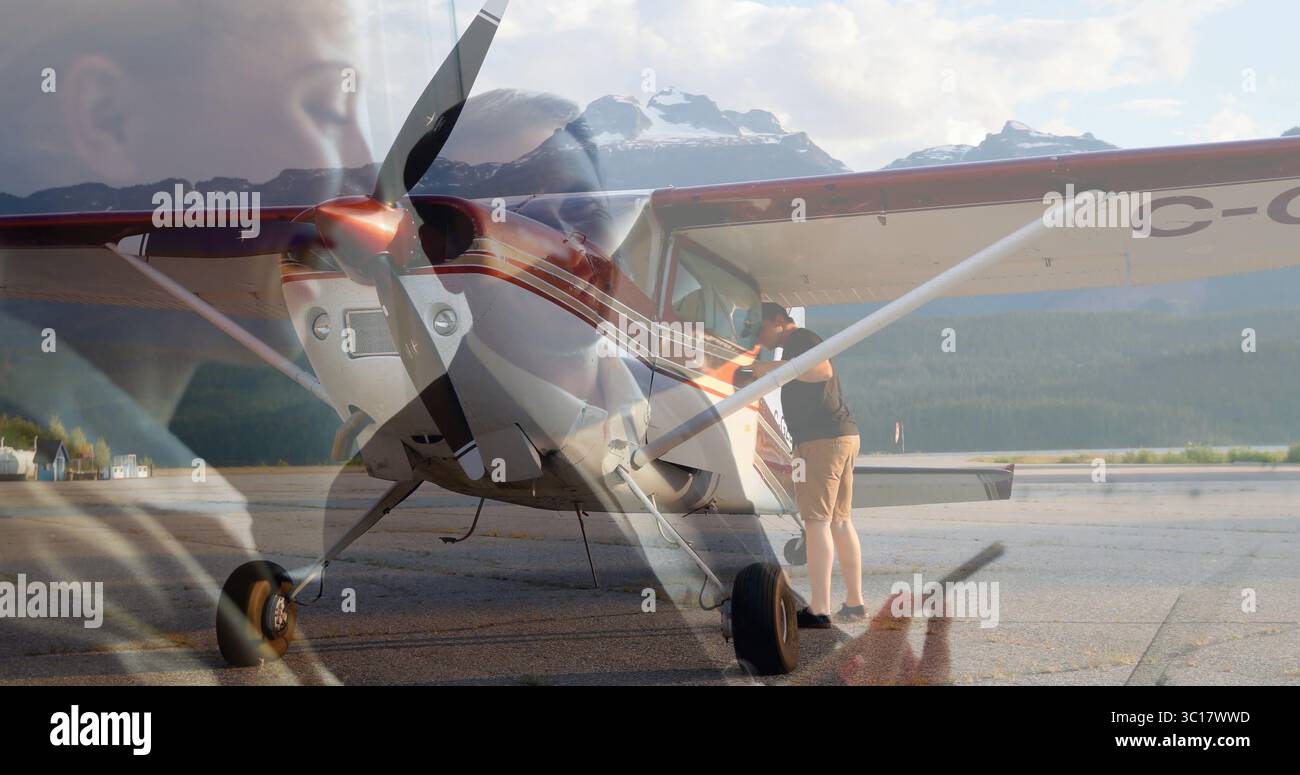 Ein angelehnter Mann inspiziert ein einmotoriges Flugzeug auf dem Vorfeld der Flugbahn, mit Smartphone-Doppelbelichtung Stockfoto