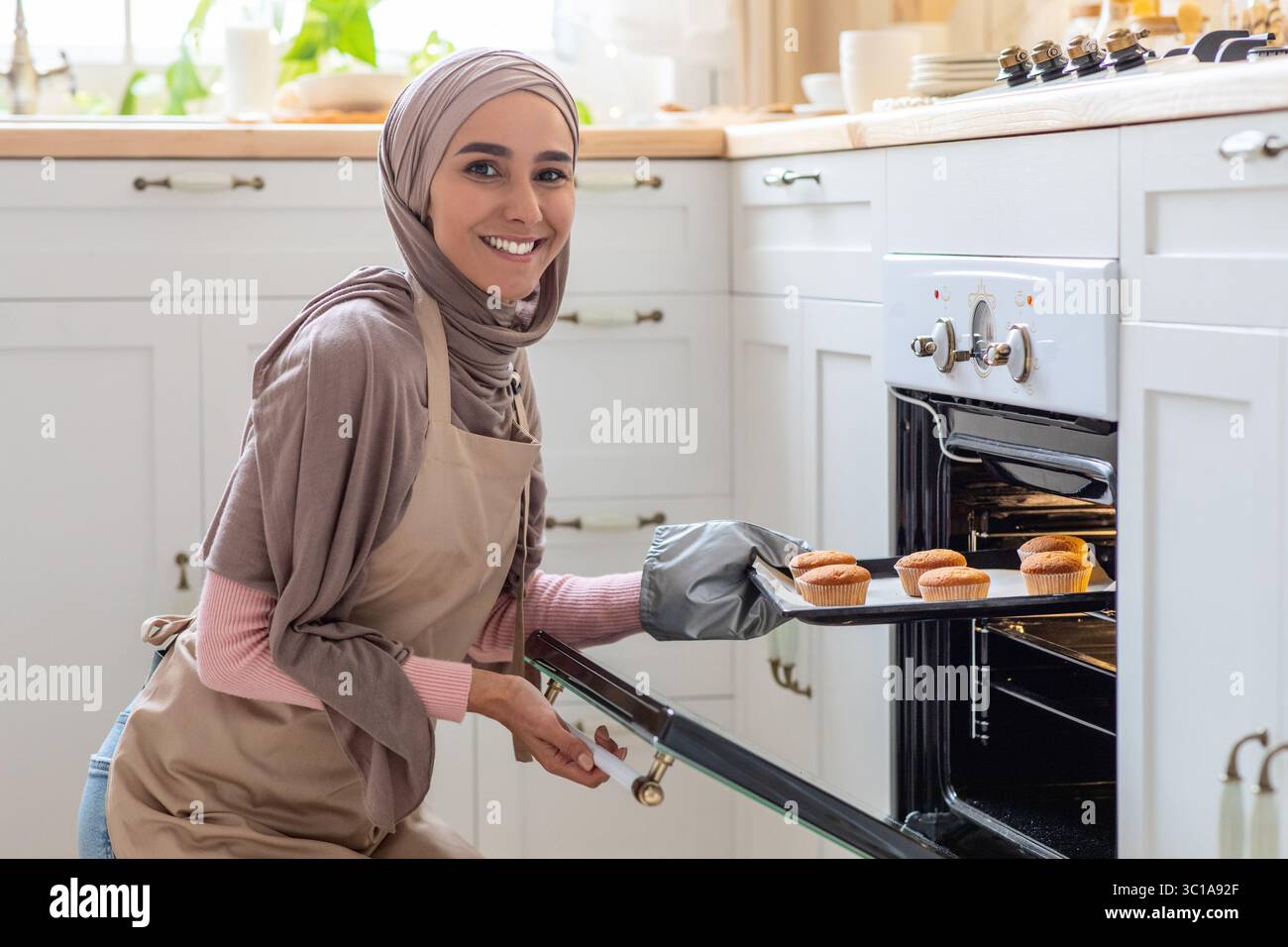 Muslimische Hausfrau. Porträt Einer Lächelnden Frau Im Hijab Baking In Kitchen Stockfoto