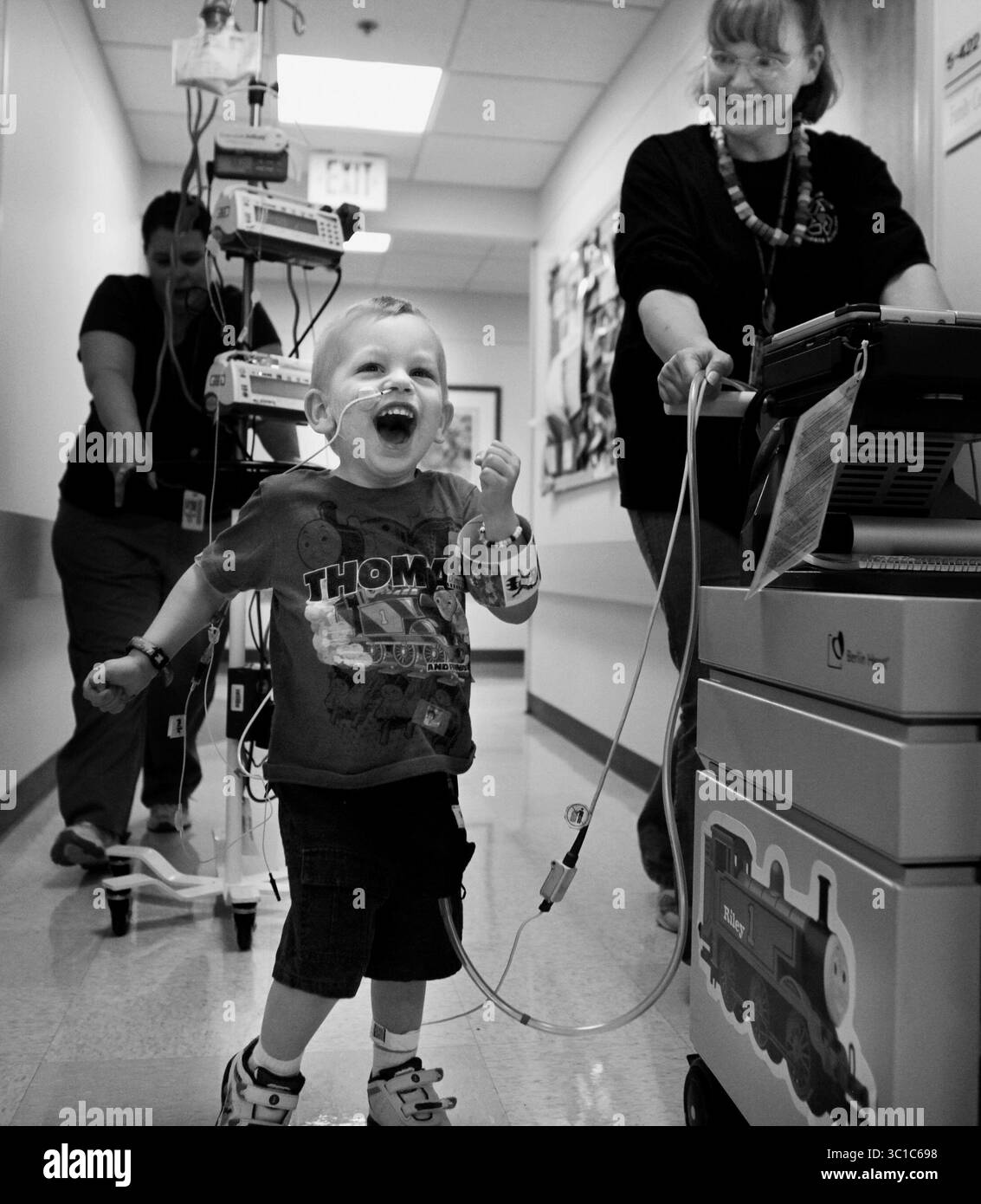 Richard Tsong-Taatarii/ 22.07.09;von links nach rechts: Auf der Intensivstation des U of M Amplatz Kinderkrankenhauses bekommt Riley Stearns seine Bewegung, indem er mit dem Berliner Herzpumpenassistenten umherfährt, der ihn am Leben hielt, während er auf eine Herztransplantation wartete. Seine Mutter, Peggy, schiebt die Maschine, mit der Riley fast ein Jahr lang mit ihm verbunden war. Riley starb, als eine der Röhren seines Berliner Herzens riss. Er hat das Krankenhaus nie verlassen. Bei der Beerdigung ihres Sohnes am 6. März sagte Peggy: „Dies ist ein glücklicher Tag“. Riley kam endlich nach Hause, wo er frei laufen konnte. (Cred Stockfoto