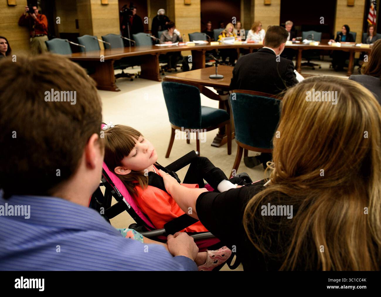 10. April 2014 – St. Paul, Minnesota, USA – Angie Weaver tröstete ihre Tochter Amelia, 7 Jahre alt, bei der Anhörung. Amelia leidet an einer seltenen Form der Epilipsie, dem Dravet-Syndrom, das mit einer Substanz aus Marihuana wirksam behandelt werden kann, die derzeit illegal ist. Der Minnesota Senate Committee on Health, Human Services and Housing hielt eine öffentliche Anhörung über ein Gesetz ab, das legalen Zugang zu medizinischem Marihuana für Menschen mit bestimmten schwächenden medizinischen Erkrankungen gewähren würde. Die Anhörung fand im Minnesota State Capitol in St. Paul, MN, statt. Donnerstag, 10. April 2014 (Bild: Glen Stubb Stockfoto