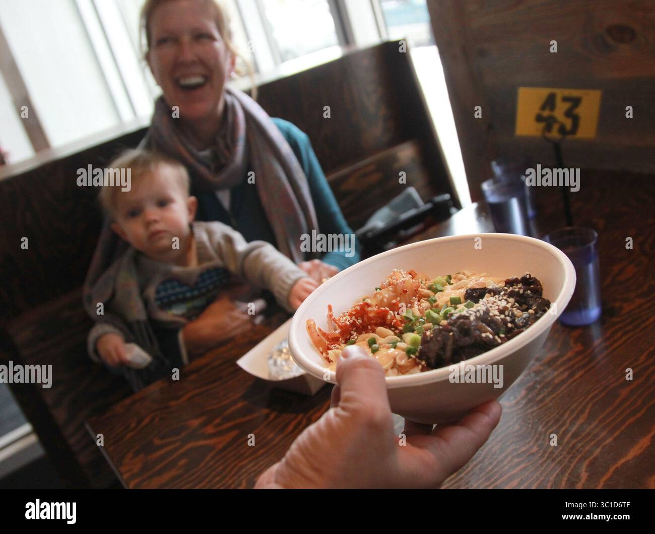 31. Januar 2013 – Minneapolis, MN, USA – Oma Sara Lorenz hält Baby Sidney als Sohn, Jesse Lorenz bekommt seinen Yum Yum Bowl bei WSK. (jesse nicht auf Foto.)    Rezension der World Street Kitchen, Küchenchef Sameh Wadi und sein Mitbesitzer Bruder Saed Wadi. In der Hauptgegend des Lyndale Restaurants, das tolles Essen serviert, als ob man es von einem Gourmet Food Truck bekommen würde. Das Essen: Kartoffel-Linsen-Patty, kurze Rib Yum-Yum-Schüssel, MFC-Sandwich, Fleischsalat-Verpackung, Kürbis-Taco, gesalzene Karamell-Eisbecher.Ê [   Aufgaben #20027422A  Feeburary 1, 2013  SLUG: 706711 rn020713  ZUSÄTZLICHE INFORMATIONEN: (Credit Stockfoto