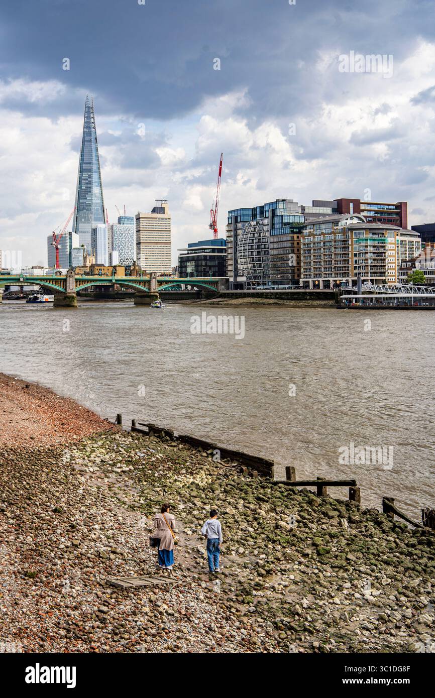 In London, England, Großbritannien, spazieren die Menschen entlang des Sanddamms der Themse mit dem Turm im Hintergrund Stockfoto