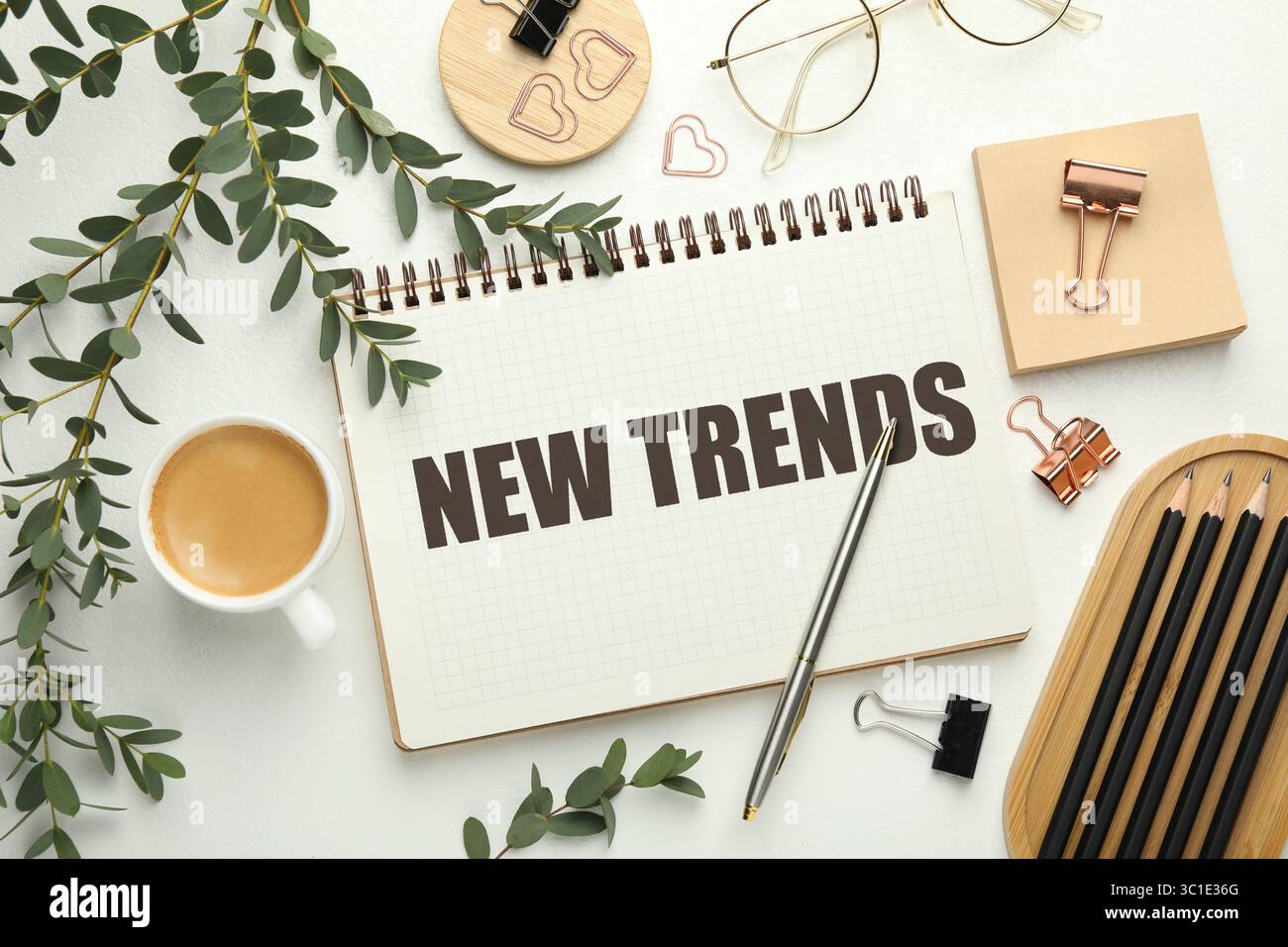 Neue Trends-Aufschrift in Notizbuch, Kaffee und Schreibwaren auf weißem Tisch, Draufsicht Stockfoto