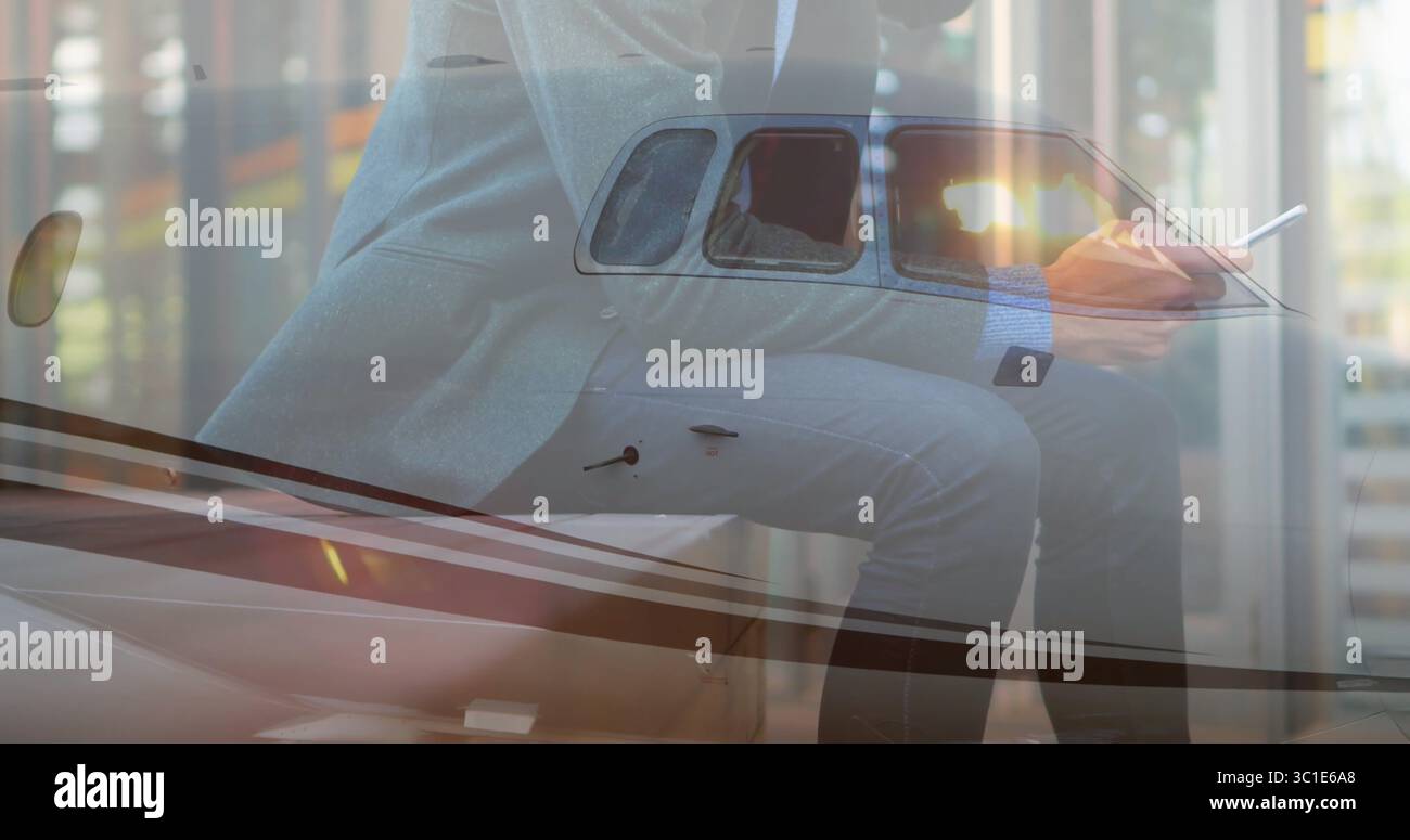 Smartphone und Stift halten, Executive im Anzug auf Jet-Flügel im Hangar, mit getöntem Fenster Stockfoto