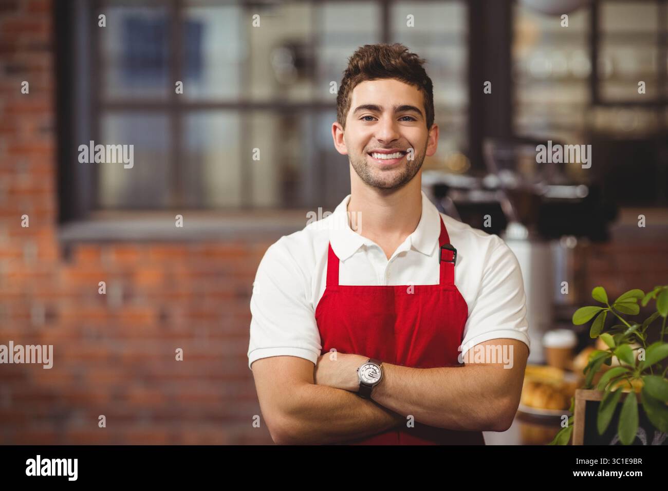 Espressomaschine zum Dampfgaren und Keramikbecher warten auf Gebäck und Topfpflanzen auf einer Backsteinplatte Stockfoto