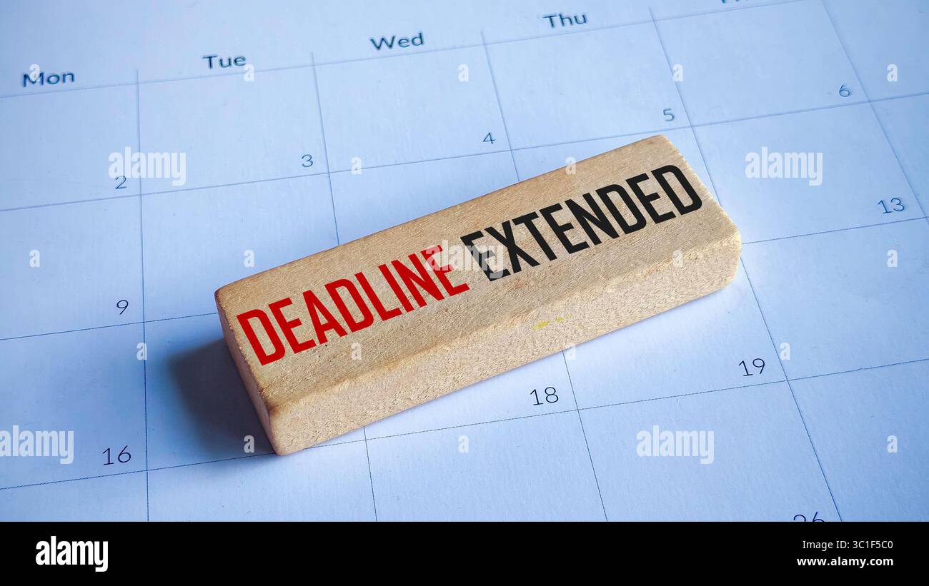Deadline Extended Text auf einem Holzblock auf einem Kalenderhintergrund Stockfoto