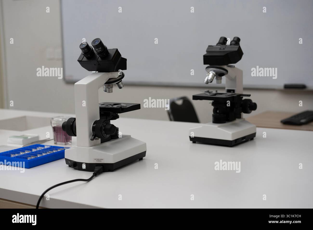 Zwei moderne Mikroskope auf einem weißen Tisch in einem Wissenschaftslabor oder Klassenzimmer. Konzept der Forschung, Bildung, Biologie und wissenschaftlichen Entdeckung. Stockfoto