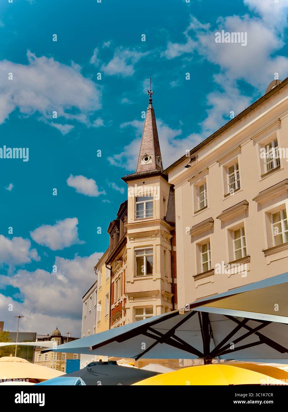 Historische Gebäude und Café-Sonnenschirme in der Altstadt von Passau, Bayern, Deutschland, unter einem blauen Himmel mit Sommerwolken. - Smartphone-aufgenommenes Stockfoto