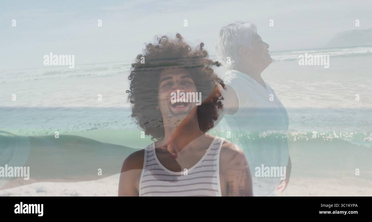 Lachender Mann in gestreiftem Tanktop am Sandstrand, mit einer Seniorin, die sich in der Nähe der Meereswellen ausdehnt Stockfoto
