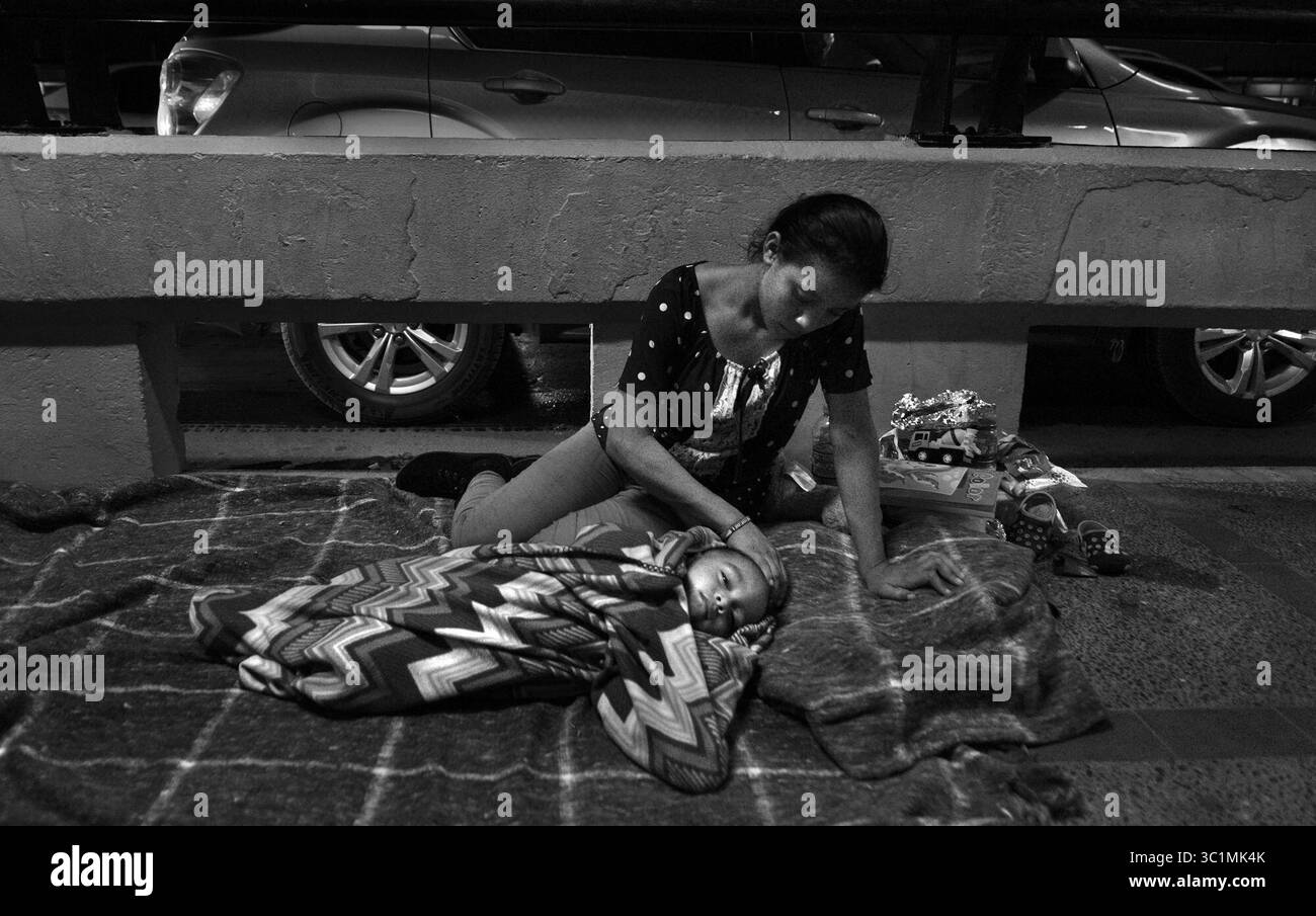 2. Juli 2018: Matamoros, Mexiko – Ingrid Perdomo, 18 Jahre alt, und ihr einjähriger Sohn Jose Luis schlafen mit anderen Asylsuchenden auf der Gateway International Bridge und warten darauf, am 2. Juli von Mexiko aus in die USA zu überqueren. Sie kam mit ihrem Gefährten Luis Miguel, 32 Jahre alt, aus Honduras, wo sie die schwierige 3-monatige Reise machten. Er sagte, er floh vor Angst und weinte viel vor Angst über seine Vergangenheit. Seine Ex-Frau fing an, mit einem Bandenmitglied auszugehen, und die Gang zündete sein Haus an und tötete seine beiden Kinder darin. Er floh in die Berge, um Sicherheit zu suchen, wo er Ingrid traf und sie ein weiteres Kind hatten. Wenn sie anfangen Stockfoto