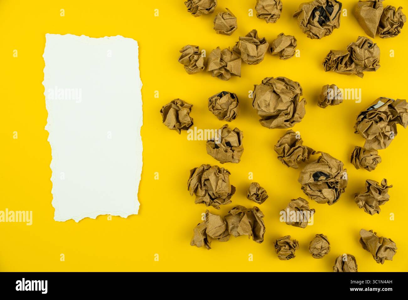 Zerknitterte braune Papierkugeln um ein weißes zerrissenes Papierblatt in der Mitte, Ideen, Brainstorming und Denkkonzept Stockfoto