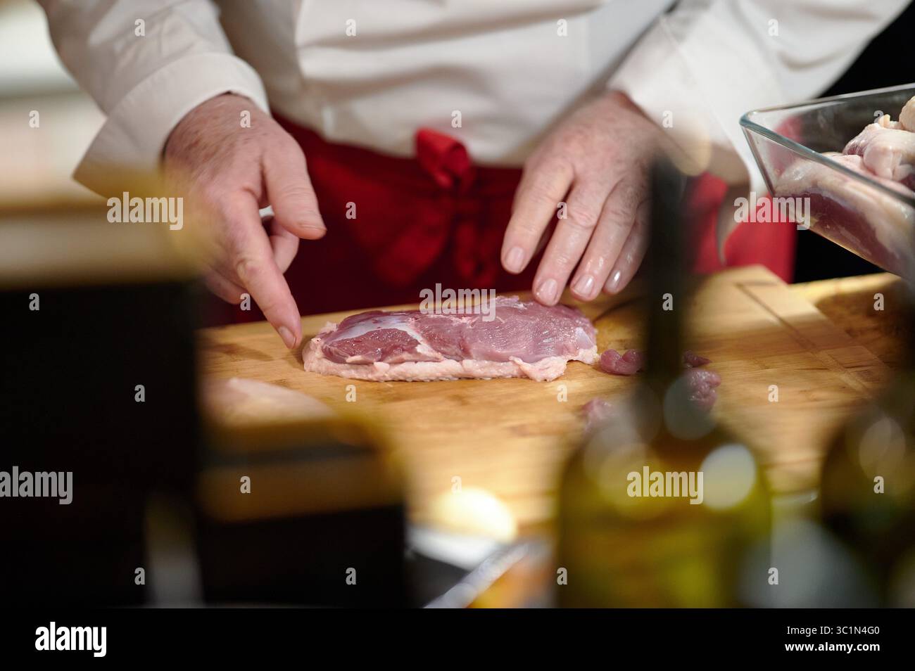Chef demonstriert Fleischschneidtechnik auf Holzbrett in der Küche Stockfoto