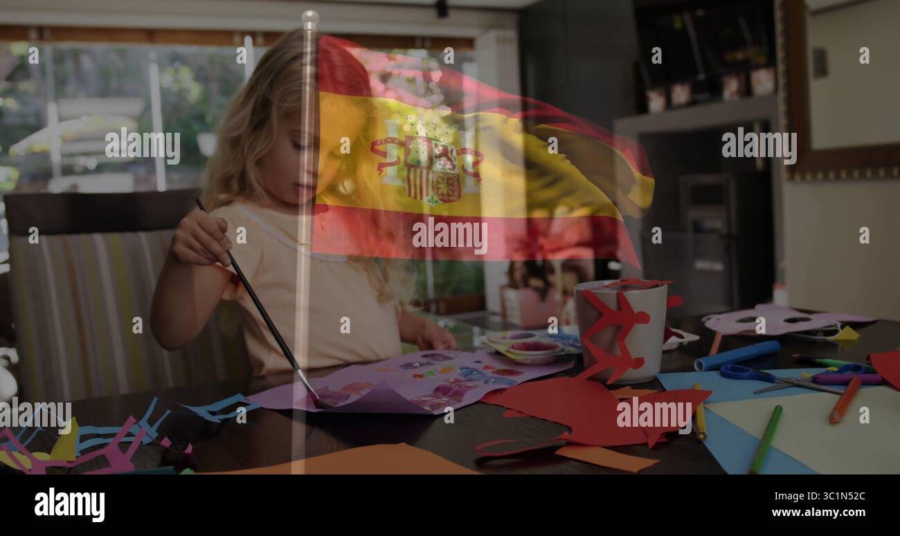 Mädchen im kurzärmligen Hemd Malpapier zu Hause, mit Pinselschere, spanischer Flagge überlagert Stockfoto