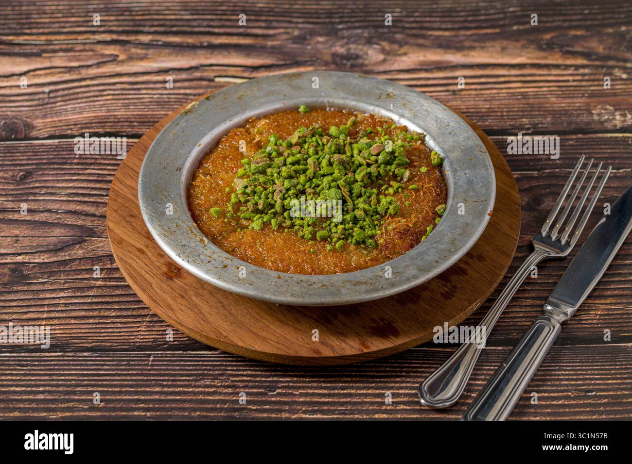 Traditionelle Kunefe mit Pistazien auf einem Holztisch Stockfoto