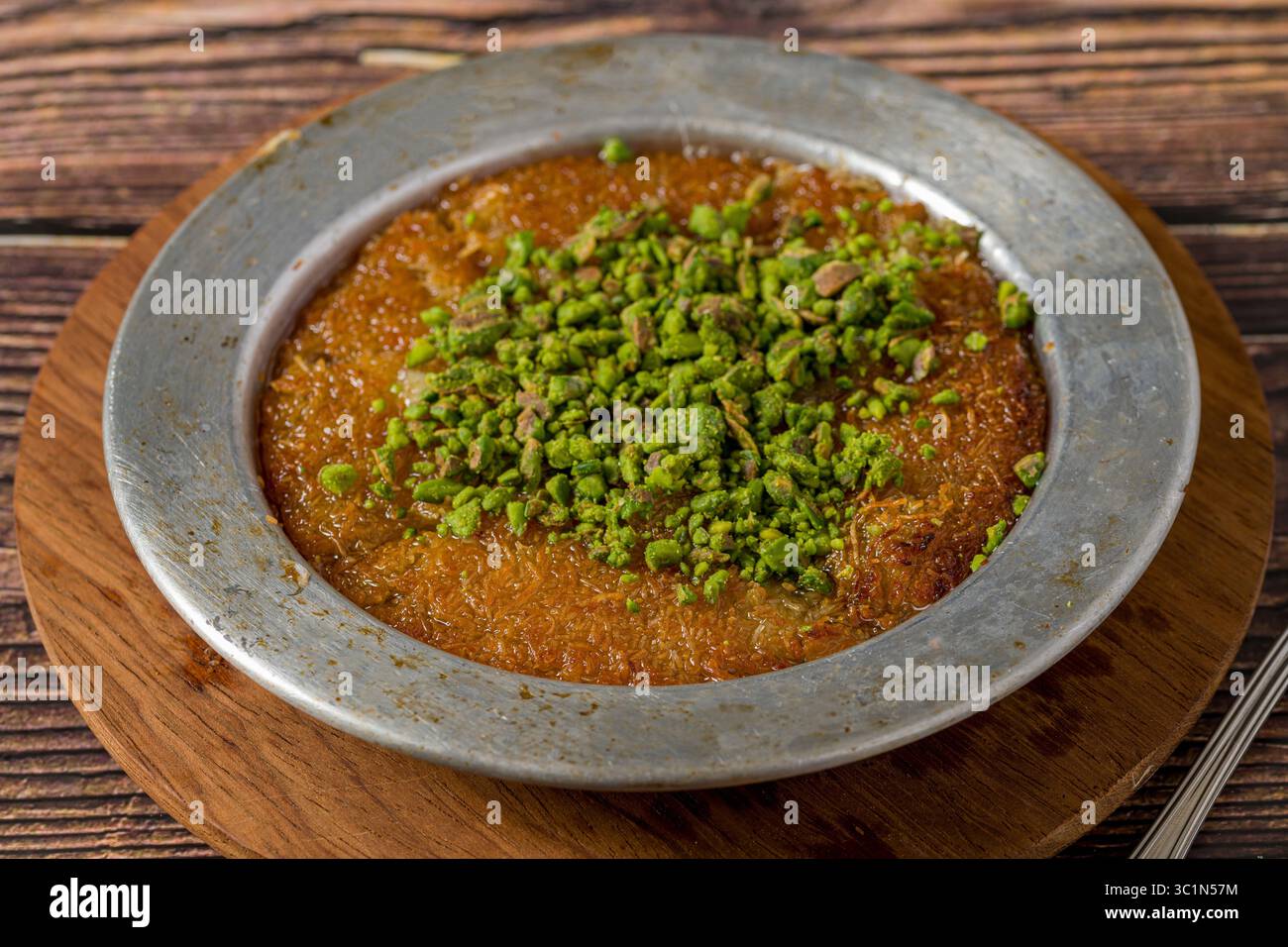Traditionelle Kunefe mit Pistazien auf einem Holztisch Stockfoto