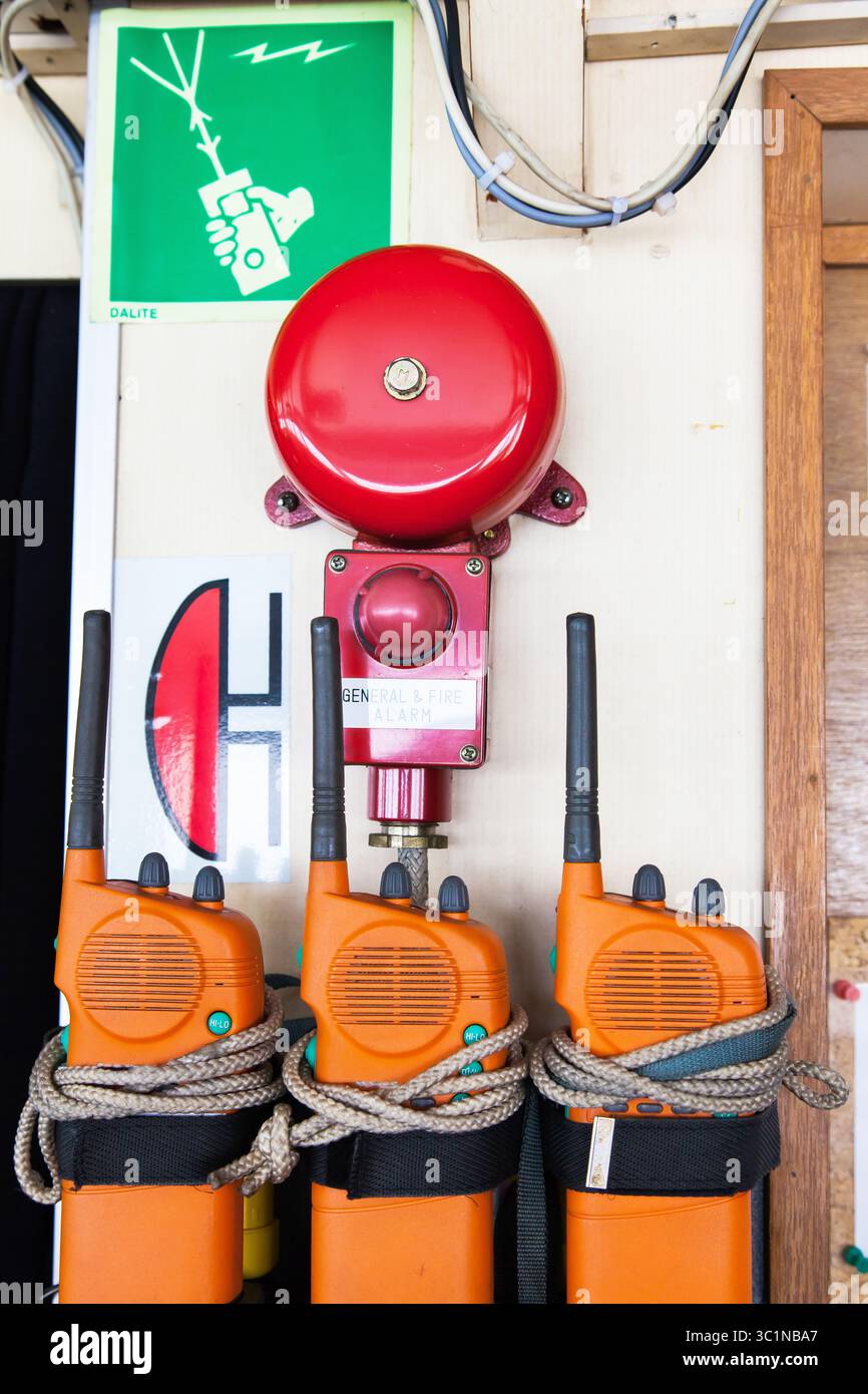 Drei orange Notrufradios auf einem Schiff in der Nähe eines Alarms. Bei einem allgemeinen Alarm oder einem Feueralarm anwenden. Stockfoto