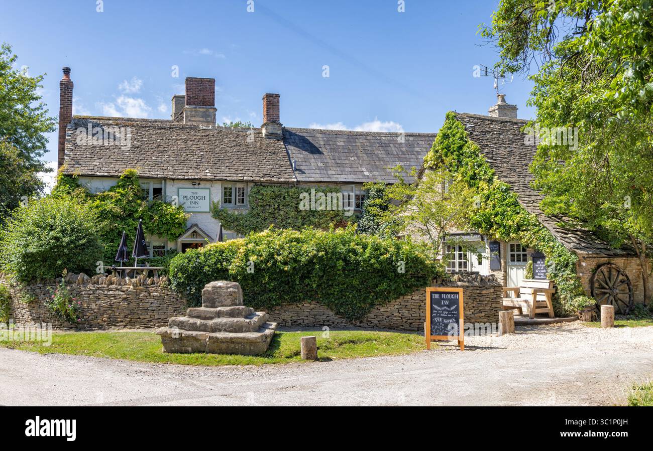 The Plough Inn, ein traditioneller Country Pub aus dem 17. Jahrhundert im Dorf Kelmscott, West Oxfordshire, Großbritannien. Die Cross-Basis vor dem Stockfoto