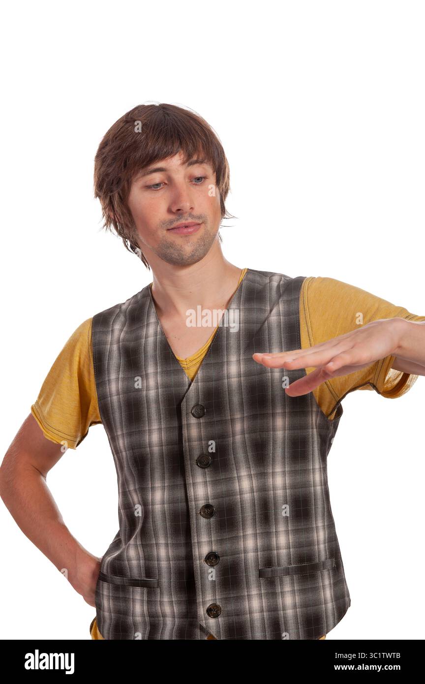 Ein junger Mann mit zotteligen Haaren posiert selbstbewusst in einer Weste und einem lustigen T-Shirt. Stockfoto
