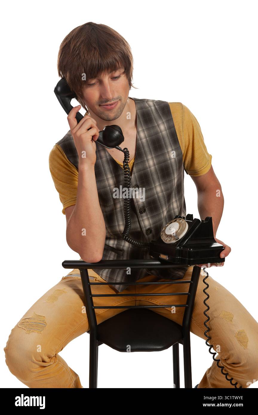 Ein junger Mann genießt einen nachdenklichen Moment am Telefon, der Vergangenheit und Gegenwart verbindet. Stockfoto