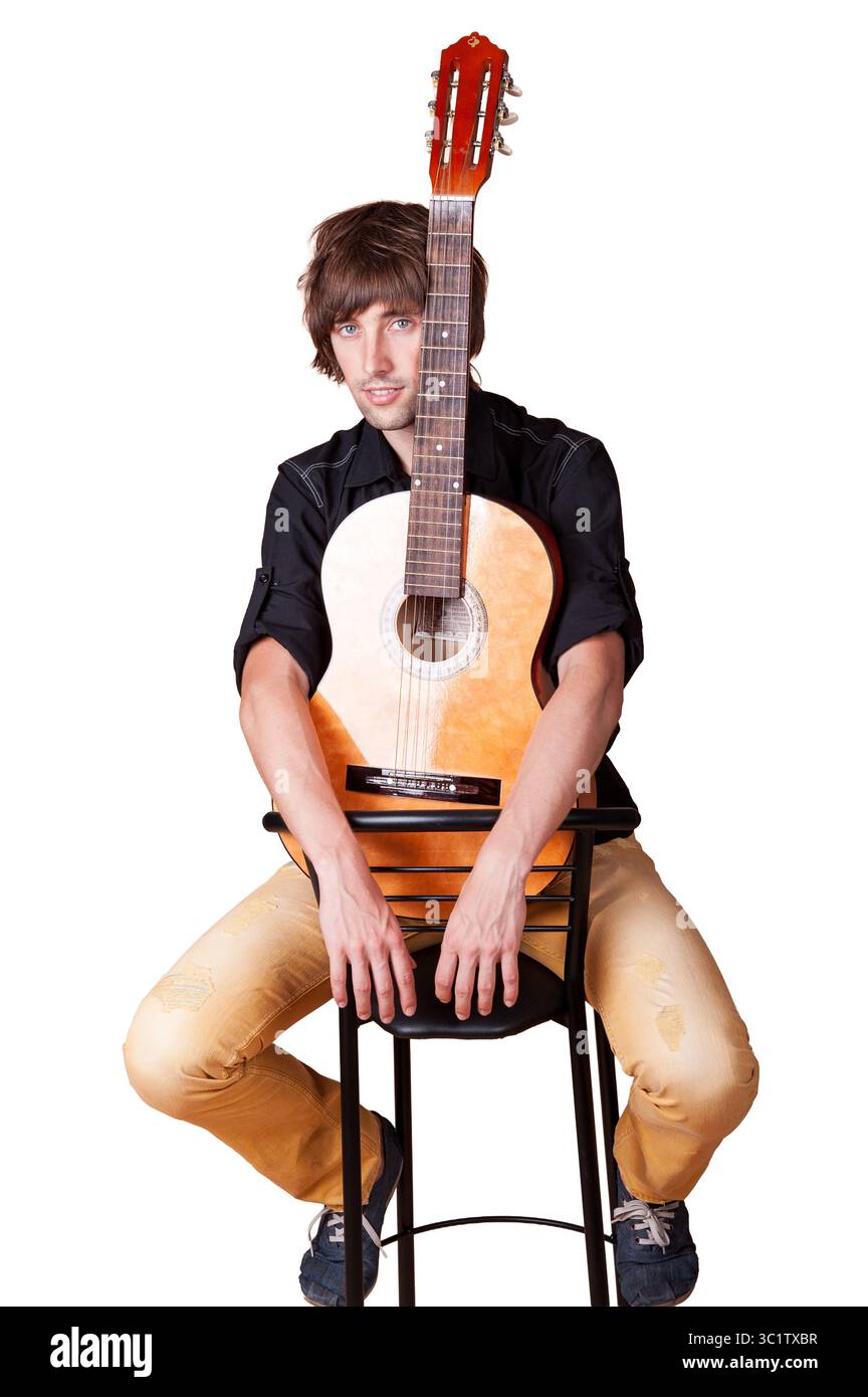 Ein Mann posiert mit einer Gitarre in einer lebendigen Studioumgebung. Stockfoto