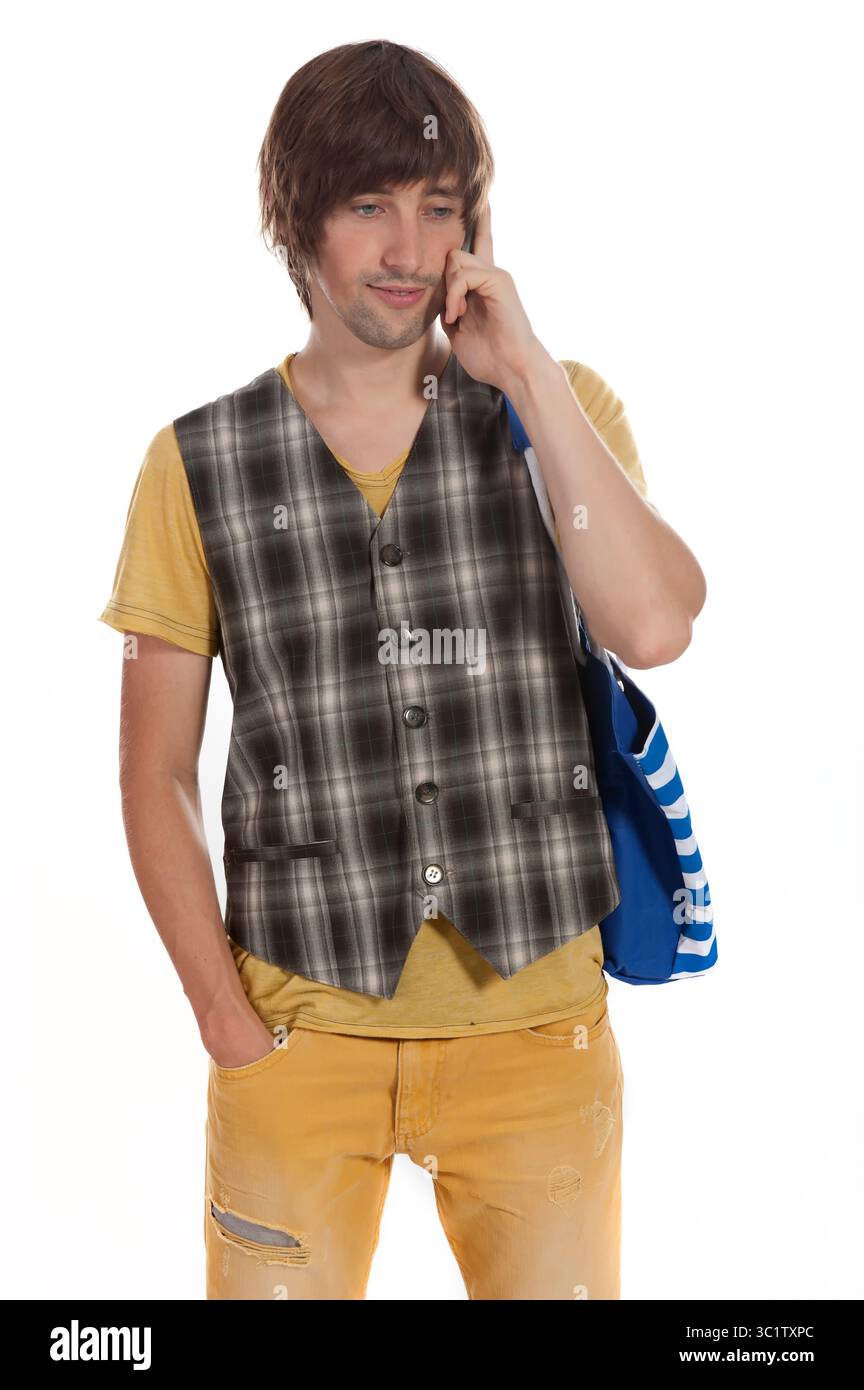Ansprechende Gespräche am Telefon, während er ein trendiges Outfit mit einer hellen Tasche präsentiert. Stockfoto