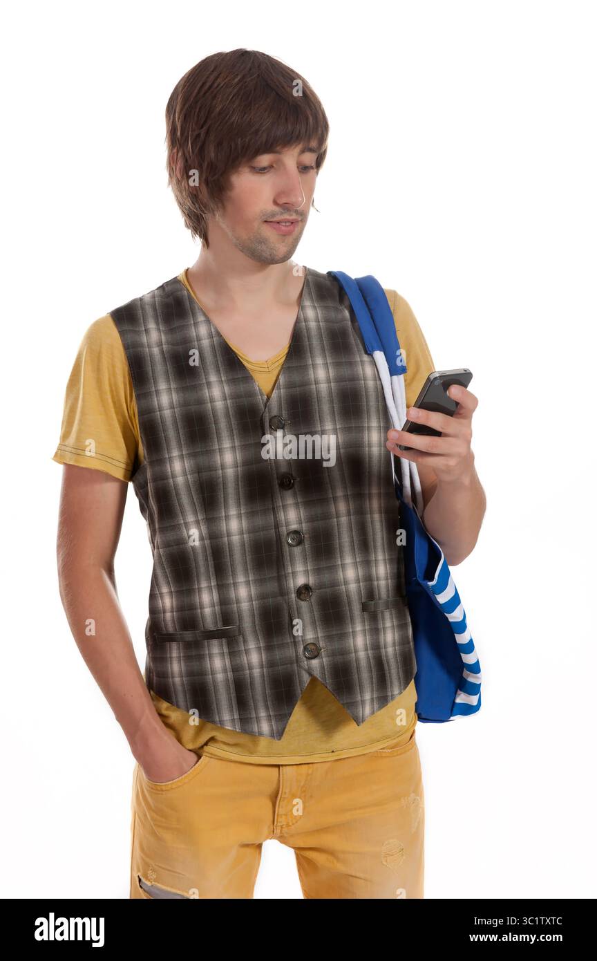 Ein Mann, der in einer karierten Weste und Jeans gekleidet ist, überprüft sein Smartphone mit einem durchdachten Look. Stockfoto