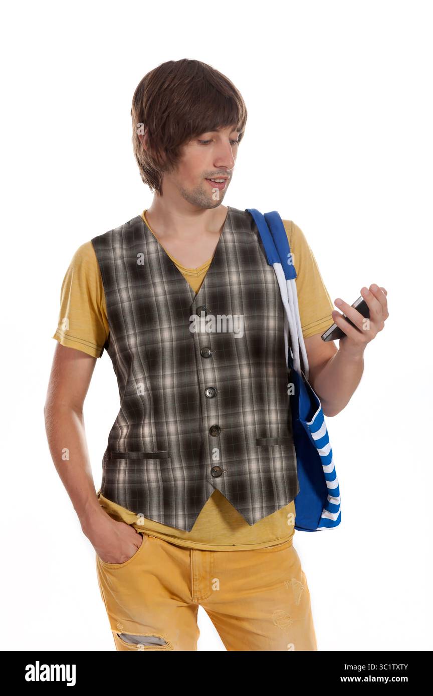 Ein junger Mann in lässiger Kleidung überprüft sein Smartphone mit einem entspannten Lächeln. Stockfoto