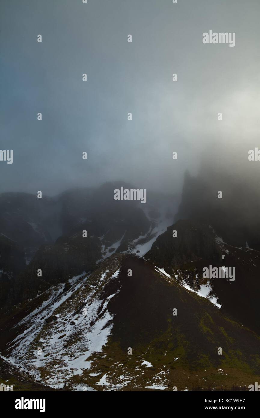 Stimmungsvoller Blick Auf Moody Wolken Und Nebel, Hervorgehoben Von Den Sonnenumhüllenden Schneebedeckten Zerklüfteten Bergen Im Inneren Islands Stockfoto