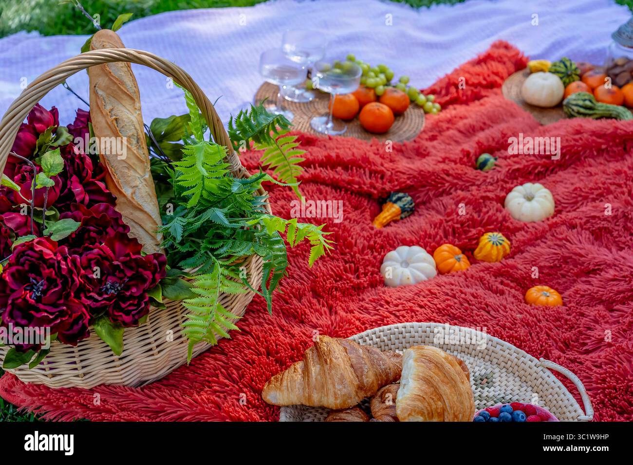 Ein lebhaftes Picknick im Herbst bietet farbenfrohe saisonale Speisen – helle Kürbisse, Äpfel, Wurstwaren, frisches Brot, Käse, und warme Getränke. Umschlossen b Stockfoto