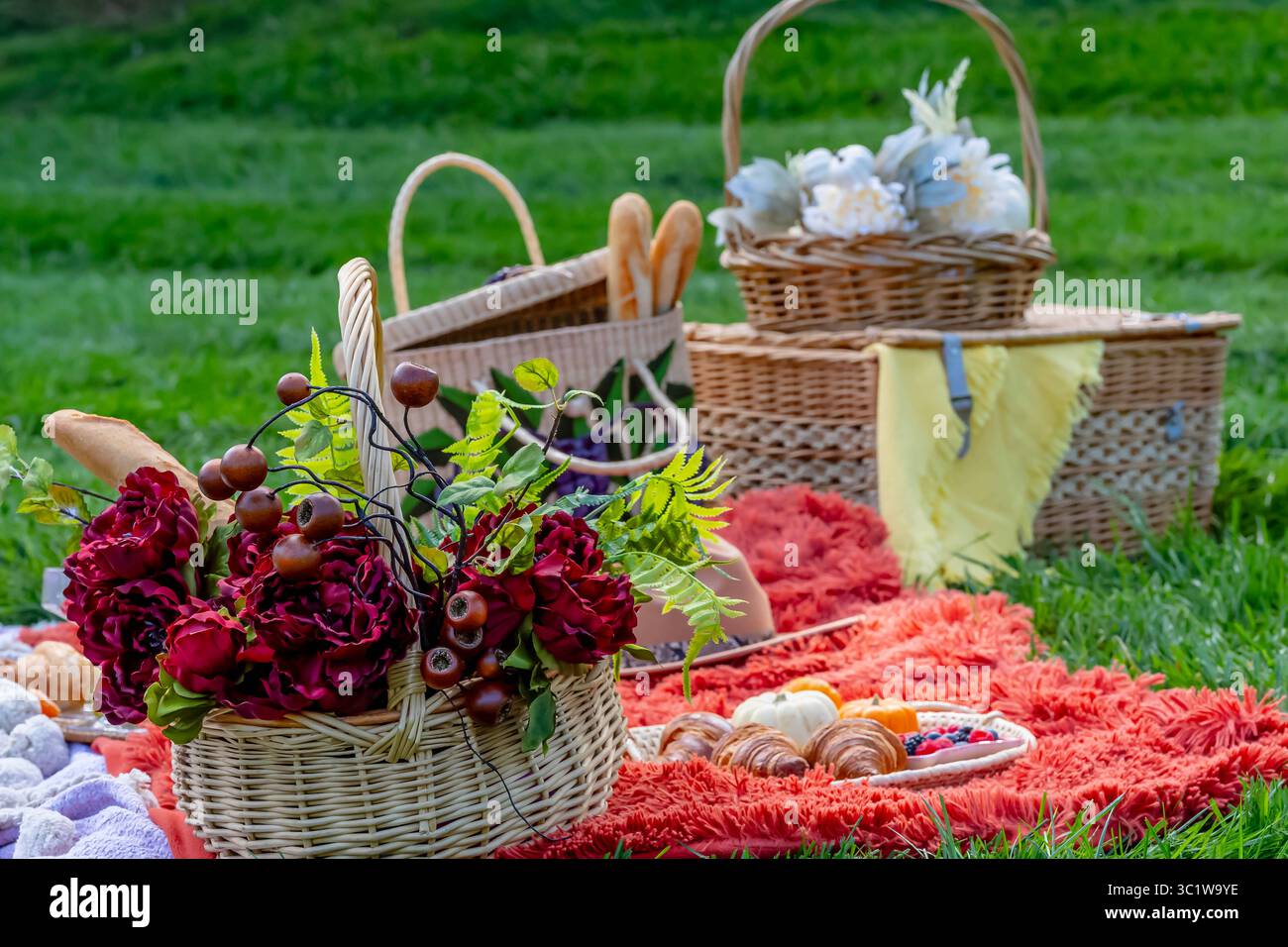 Ein lebhaftes Picknick im Herbst bietet farbenfrohe saisonale Speisen – helle Kürbisse, Äpfel, Wurstwaren, frisches Brot, Käse, und warme Getränke. Umschlossen b Stockfoto