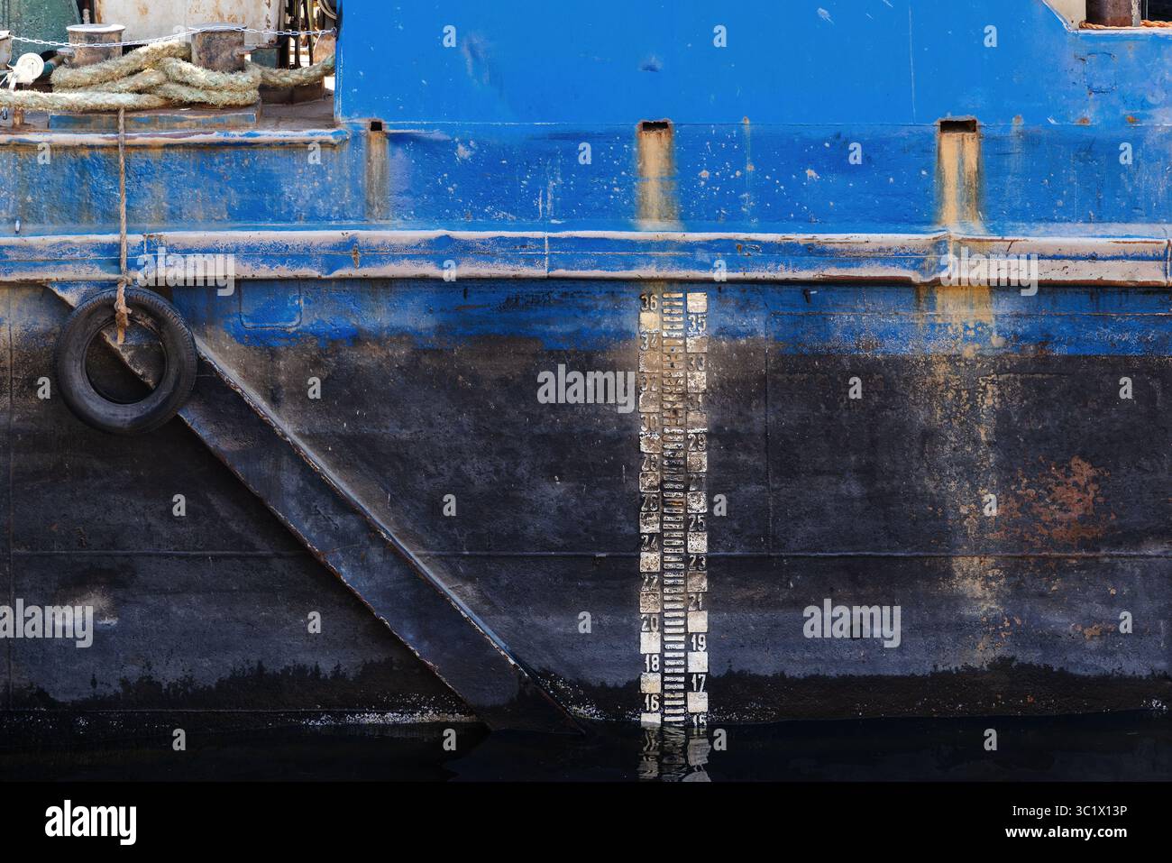 Eine detaillierte Ansicht eines verwitterten Schiffsrumpf mit vertikaler Tiefenskala, Seil und Rost Stockfoto