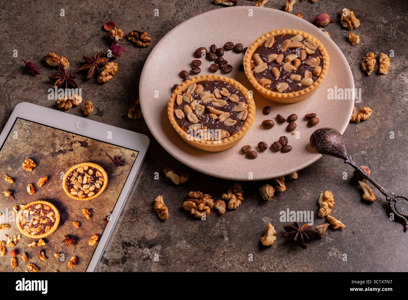 Eine rustikale, flache Keramikplatte zeigt drei kunstvoll angeordnete Kaffeetörtchen. Die Torten sind mit einer Ganache aus dunkler Schokolade gefüllt und mit Hackfleisch belegt Stockfoto