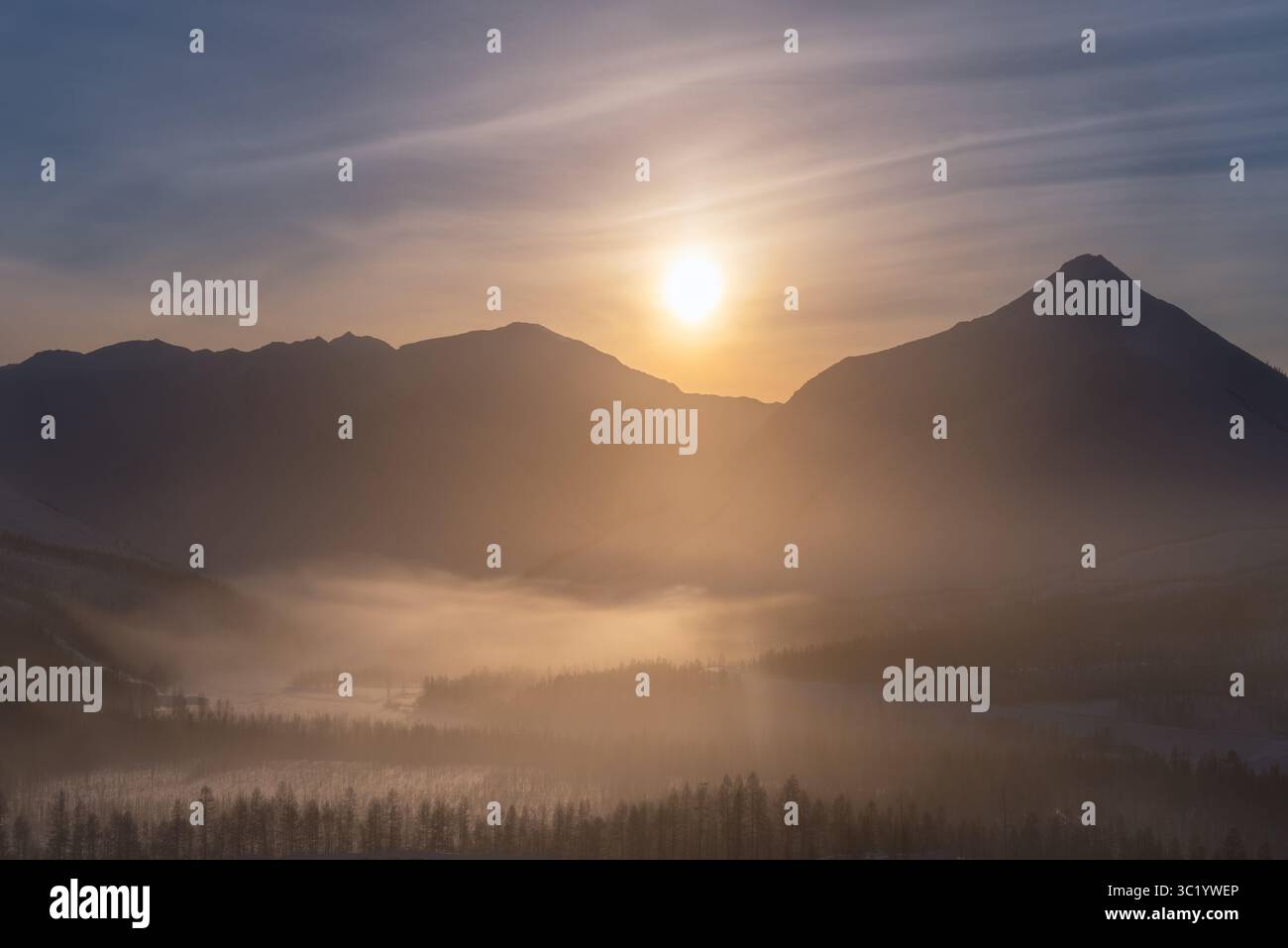 Der Blick auf den ätherischen Sonnenaufgang wirft ein goldenes Leuchten über das nebelige Tal und die zerklüfteten Gipfel und schafft eine ruhige und ehrfurchteinflößende aussicht, Magadan Oblast, Russland. Stockfoto