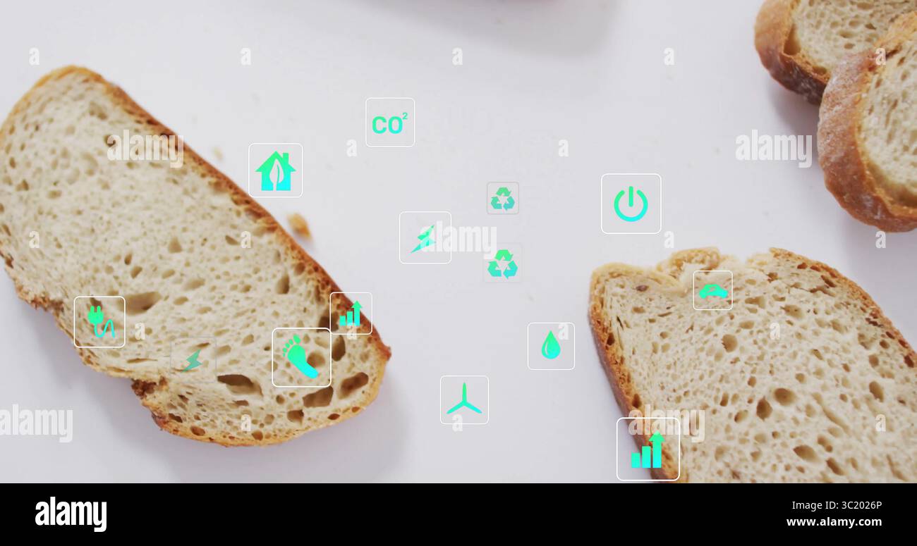 Mit knusprigen, handwerklichen Brotscheiben auf weißem Tisch mit umschwebenden Umweltsymbolen und Krümeln Stockfoto