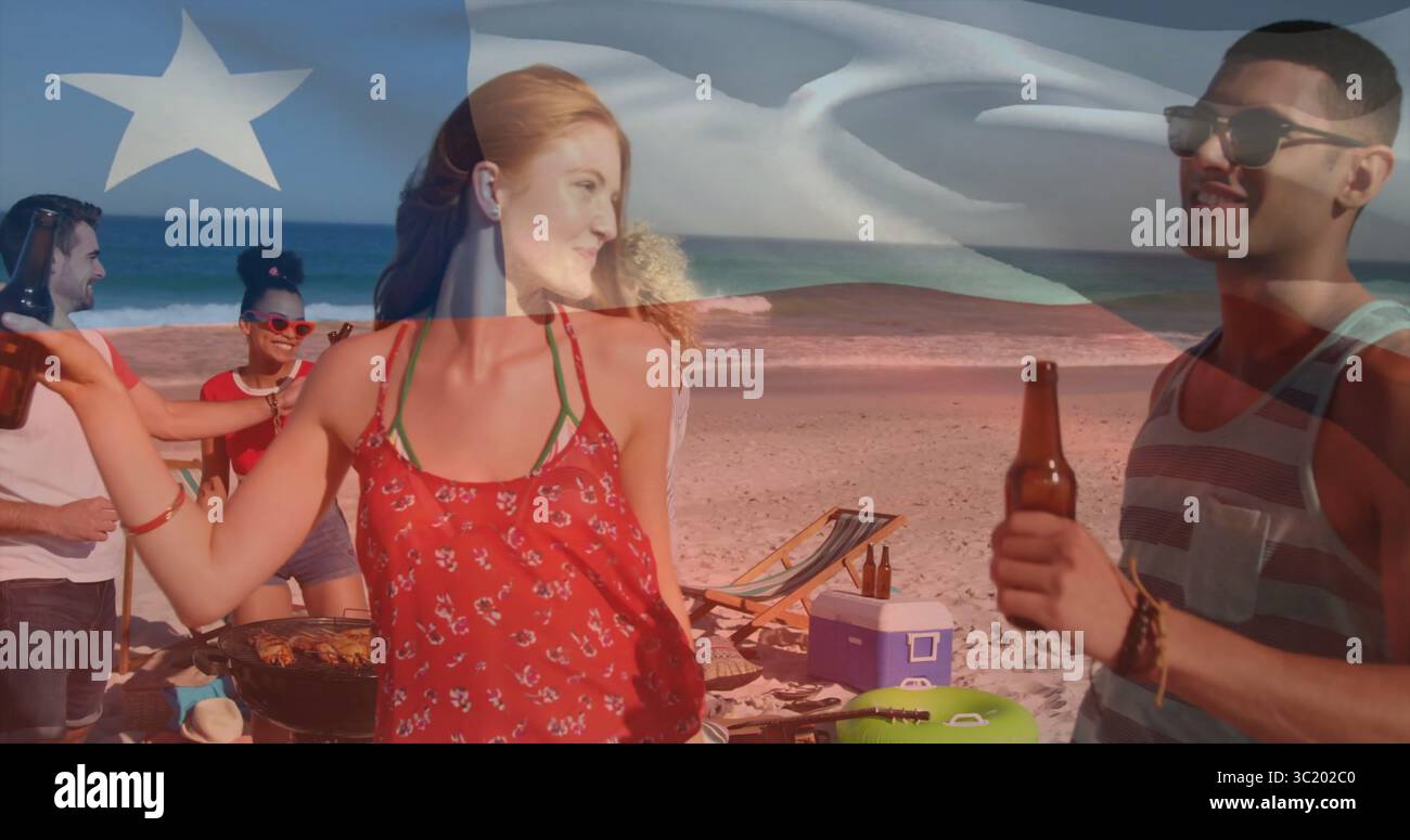 Tanzende rothaarige Frau mit rotem Oberteil und Bier am Strand bei Sonnenuntergang, mit Grill und Fahnenüberzug Stockfoto