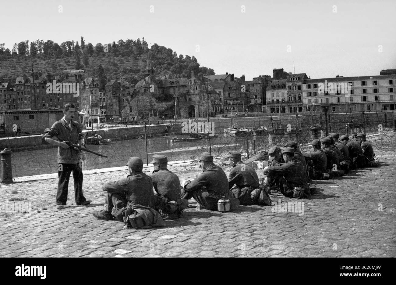 Die Befreiung von Honfleur, Normandie, Frankreich während des zweiten Weltkrieges. 26. August 1944. Ein französischer Widerstandskämpfer bewacht junge deutsche Soldaten nach ihrer Kapitulation. Stockfoto