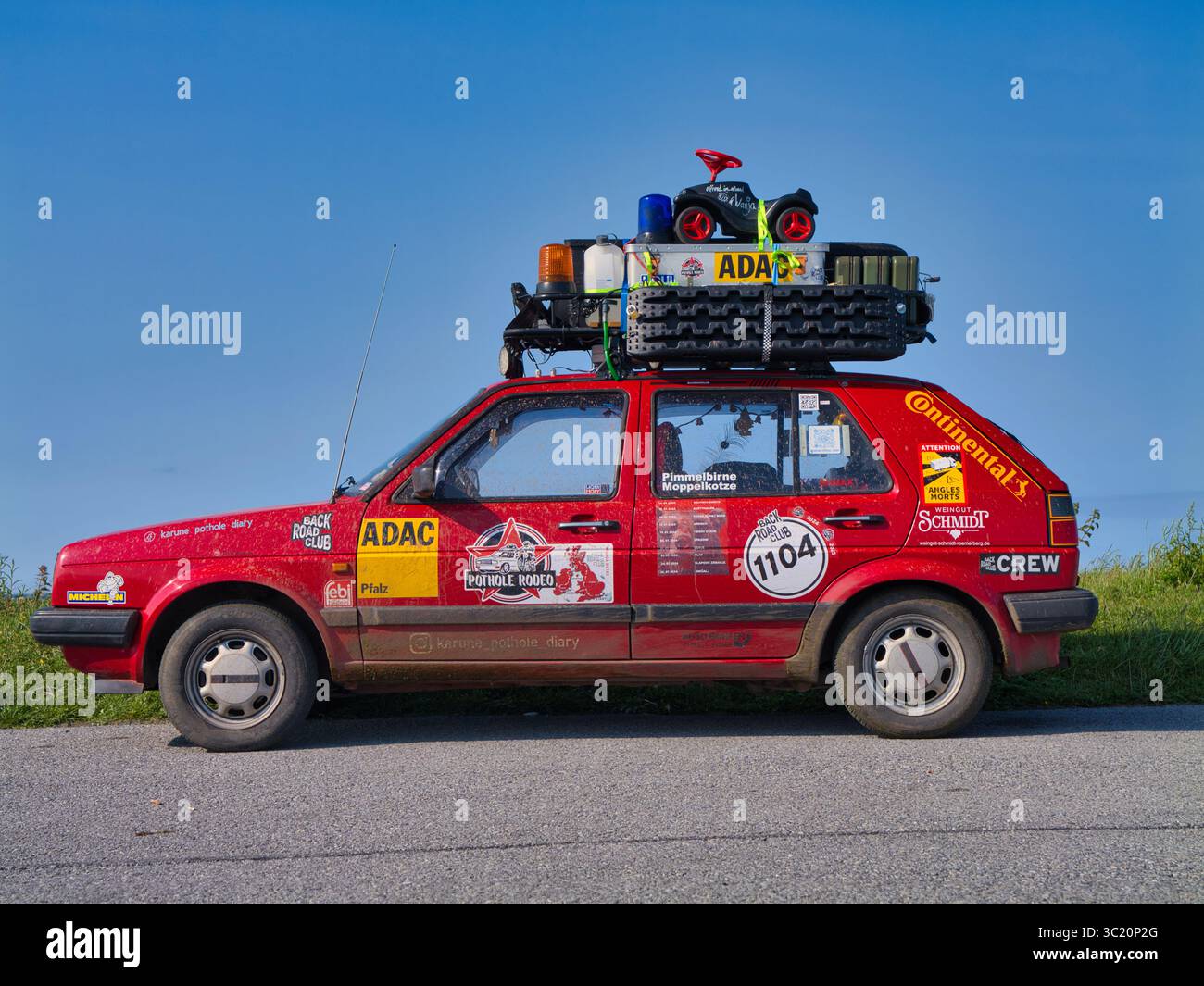 Bridges of Ross, Irland - 10. Juni 2025: Ein Rallyefahrzeug mit lebendigen Aufklebern und Gepäck auf dem Dach, das entlang der malerischen Bridges of Ross in Irland geparkt wird. Klarer blauer Himmel über dem Kopf. Stockfoto