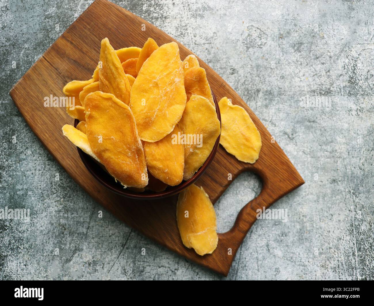 Getrocknete Mangobänder in Holzschale. In Scheiben geschnittene, dehydrierte Mangos. Stockfoto