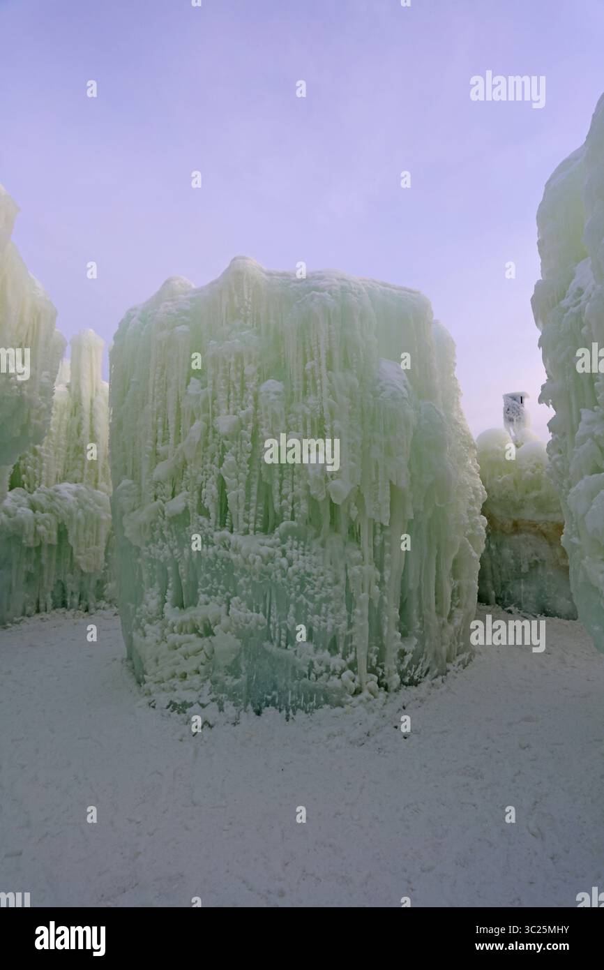 Ein Schneerad und eine große Eisskulptur, umgeben von Eiswänden, gekrönt von Eiszapfen und Schnee in Ice Castles im Genfer See, Wisconsin, USA Stockfoto