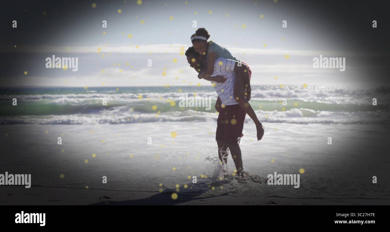 Trage Frau Huckepack, Mann in gestreiftem T-Shirt, der durch die Brandung am Strand streift, mit goldenem Licht Stockfoto
